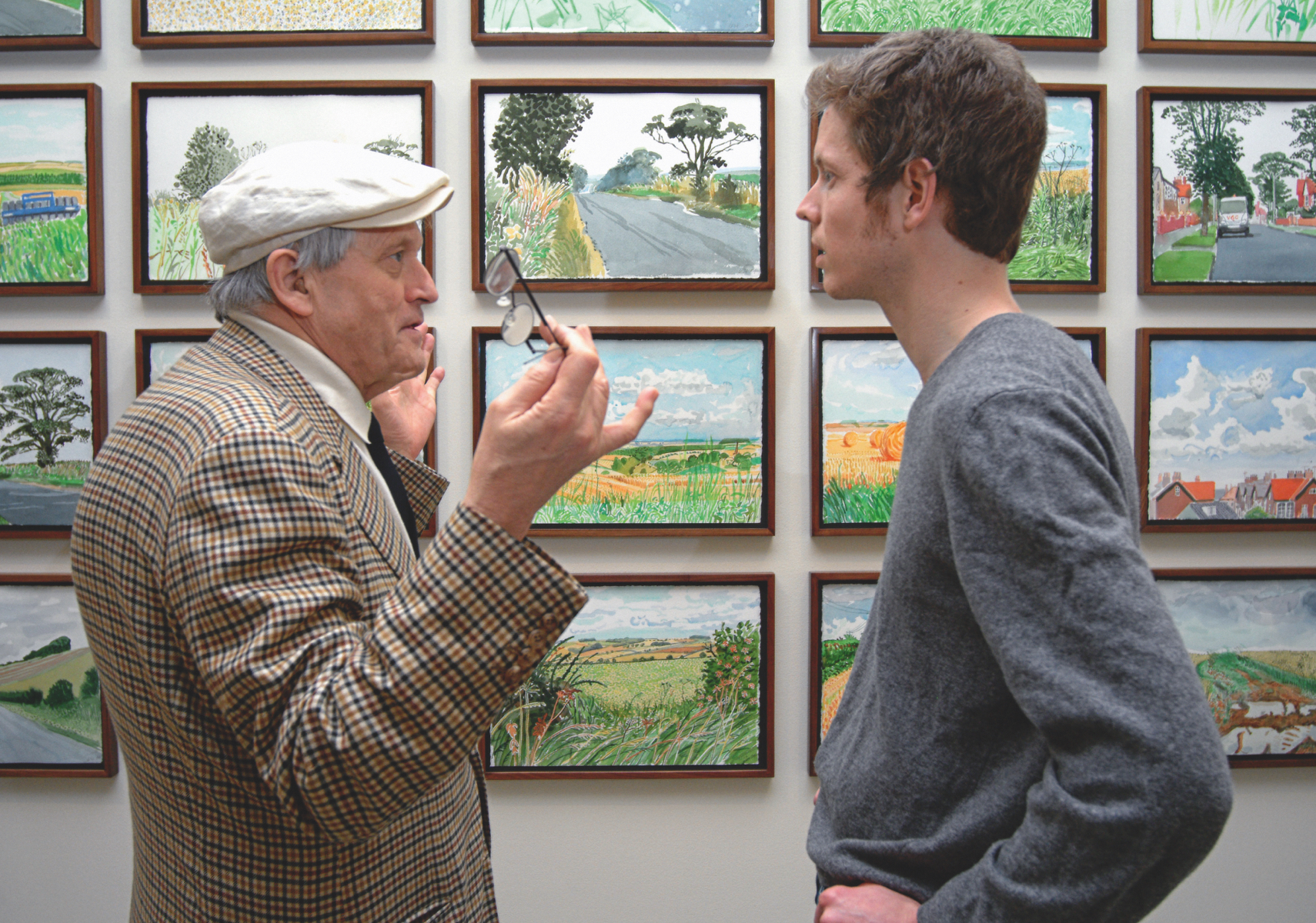Men chatting in an art gallery in front of paintings