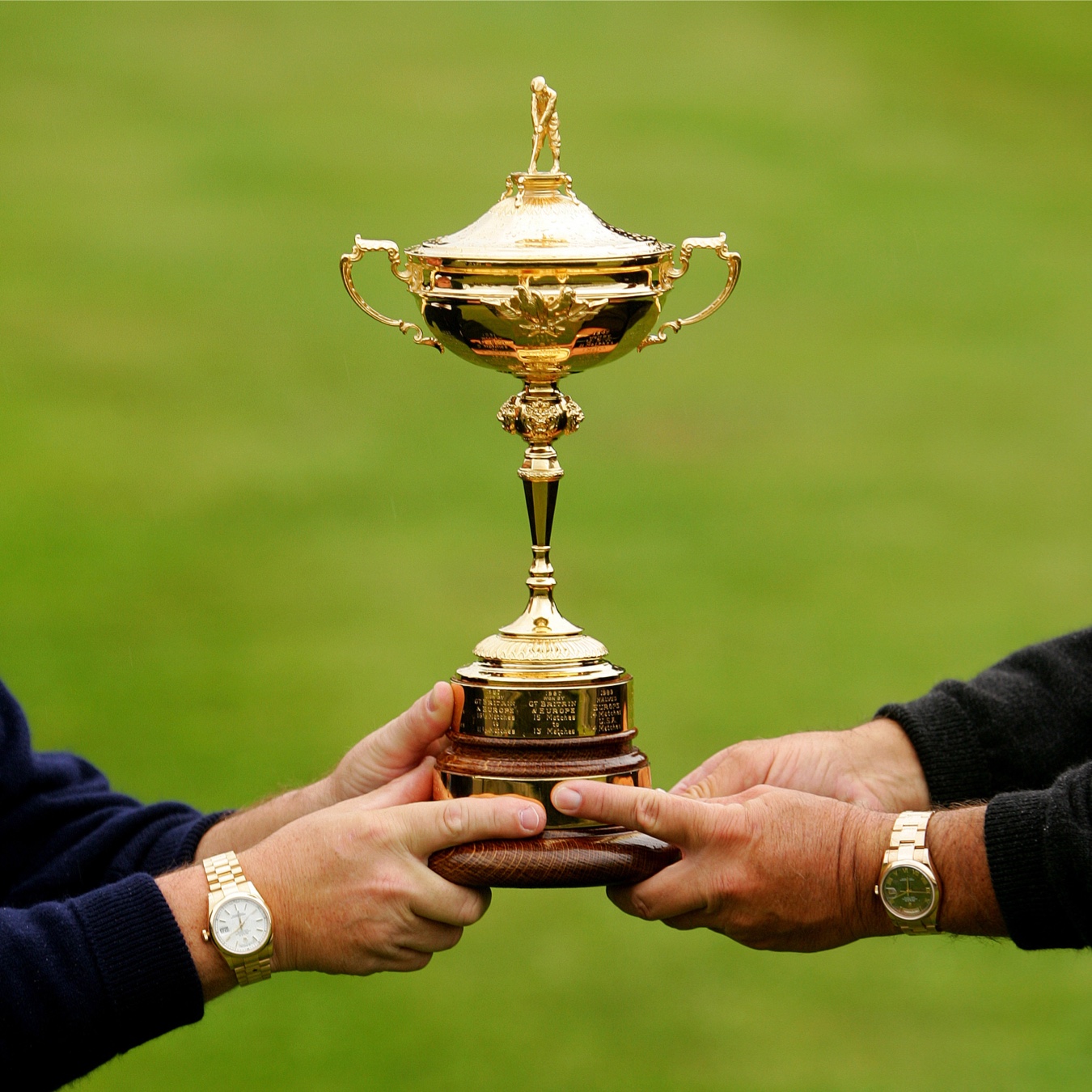 Ryder Cup trophy featuring two men wearing gold Rolex watches